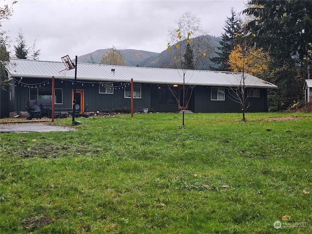 back of house featuring a lawn and a mountain view