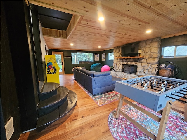 recreation room featuring light wood-type flooring, a stone fireplace, and wood ceiling