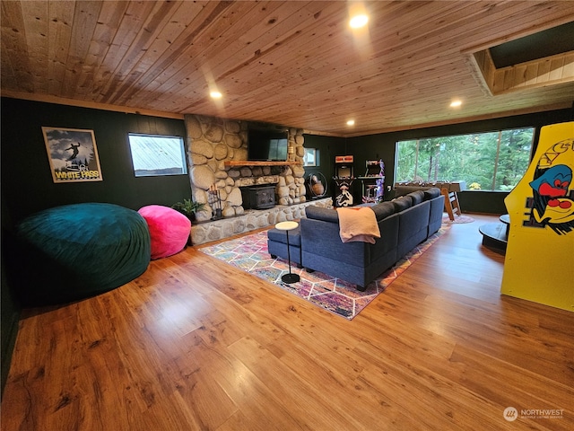 living room with hardwood / wood-style floors, a wood stove, a wealth of natural light, and wooden ceiling