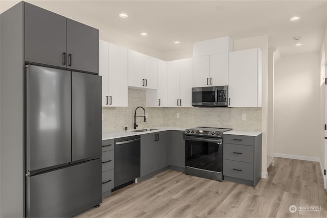 kitchen featuring appliances with stainless steel finishes, light countertops, a sink, and gray cabinetry