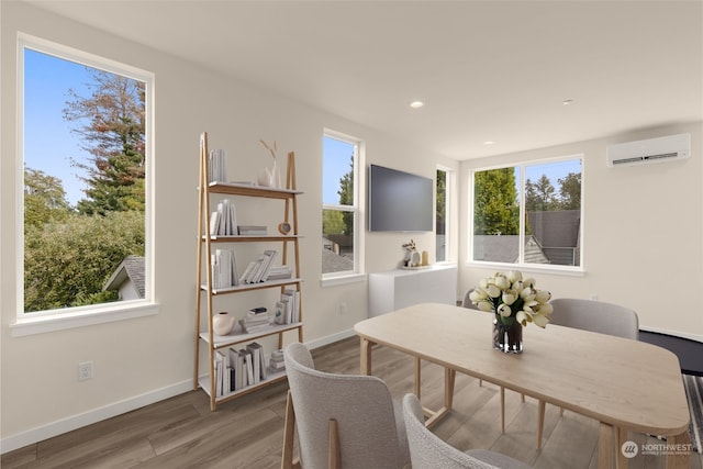 dining room featuring a wall mounted air conditioner, wood finished floors, and baseboards