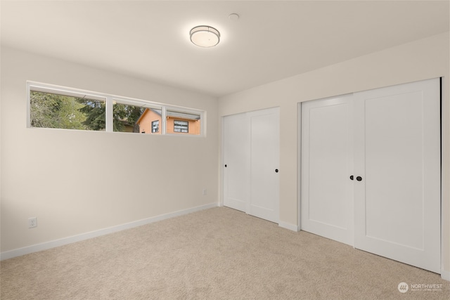 unfurnished bedroom featuring baseboards, multiple closets, and carpet flooring