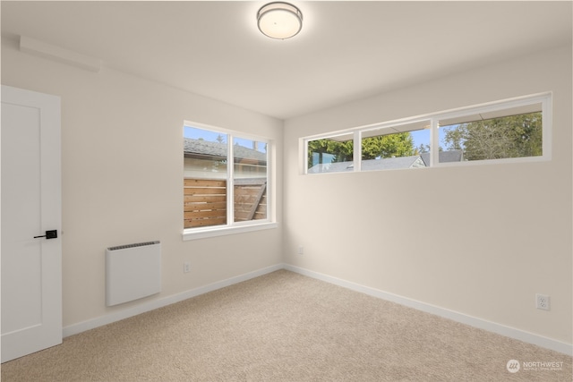 carpeted spare room featuring radiator and baseboards