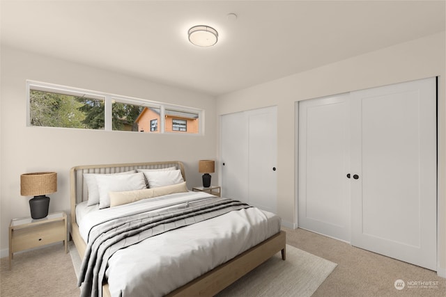 bedroom with multiple closets, light carpet, and baseboards