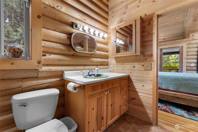 bathroom featuring tile patterned flooring, log walls, vanity, and toilet