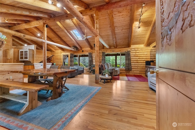 dining area with light hardwood / wood-style floors, rustic walls, wooden ceiling, and vaulted ceiling with skylight