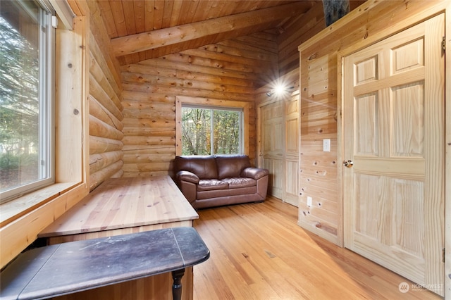 interior space featuring light hardwood / wood-style flooring, vaulted ceiling with beams, log walls, and wooden ceiling