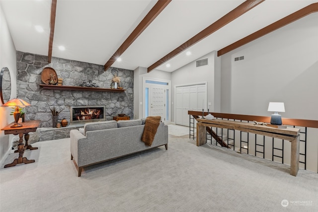 carpeted living room with lofted ceiling with beams and a stone fireplace