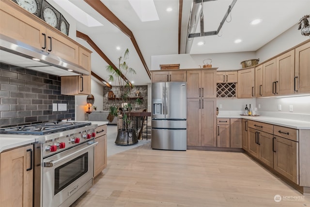 kitchen featuring tasteful backsplash, lofted ceiling with skylight, stainless steel appliances, and light hardwood / wood-style floors