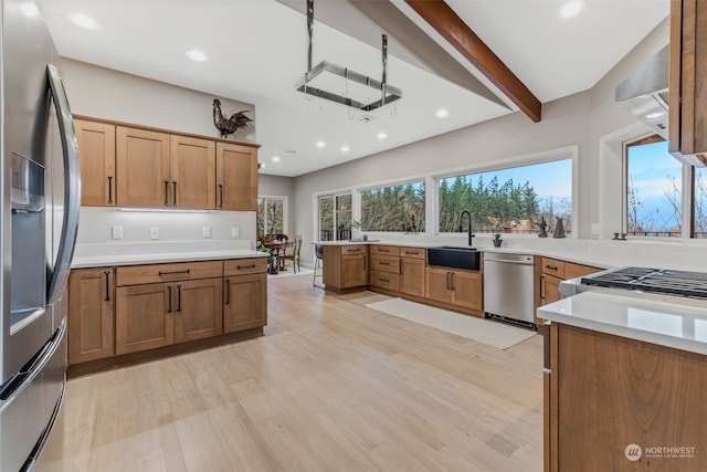 kitchen featuring sink, light wood-type flooring, beamed ceiling, stainless steel appliances, and extractor fan