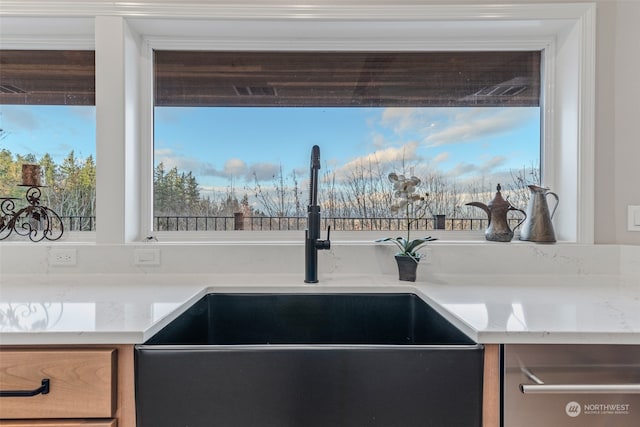 kitchen featuring light stone counters and sink