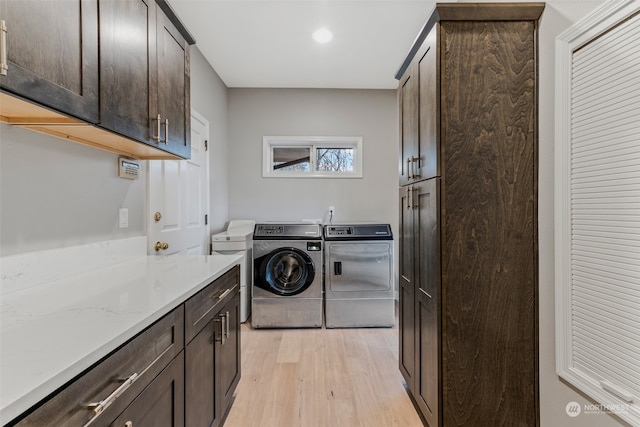 clothes washing area with light hardwood / wood-style floors, cabinets, and washing machine and clothes dryer