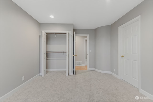 unfurnished bedroom with a closet and light colored carpet