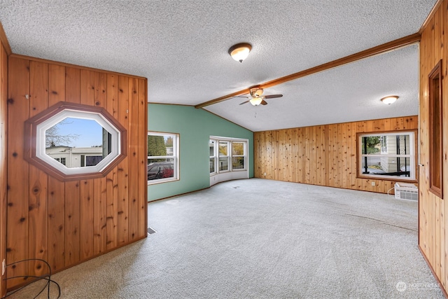 unfurnished living room featuring carpet flooring, a wealth of natural light, and wooden walls