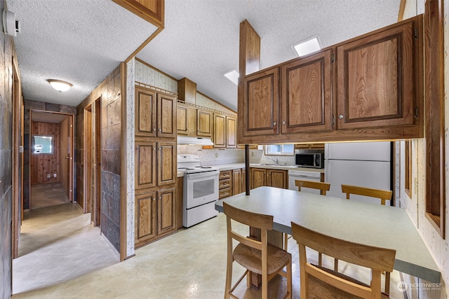 kitchen featuring a textured ceiling, vaulted ceiling, and white appliances