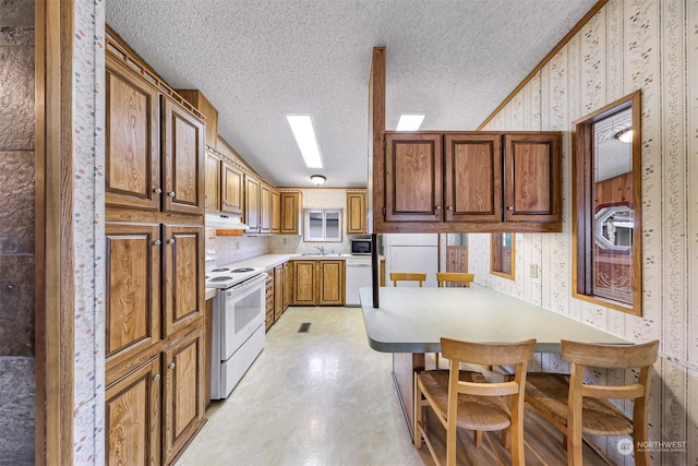 kitchen with white appliances, sink, ornamental molding, a textured ceiling, and kitchen peninsula