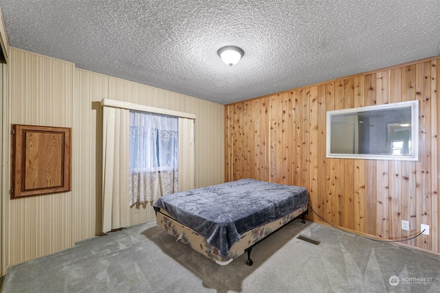 carpeted bedroom featuring wooden walls and a textured ceiling