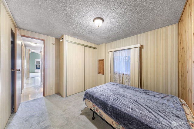 carpeted bedroom with a textured ceiling and a closet