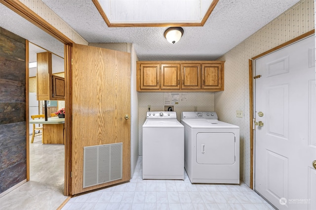 washroom with washing machine and dryer, cabinets, and a textured ceiling