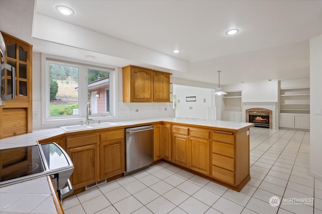 kitchen with kitchen peninsula, appliances with stainless steel finishes, sink, tile countertops, and hanging light fixtures