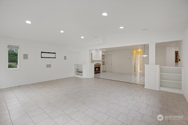 unfurnished living room with light tile patterned floors and decorative columns