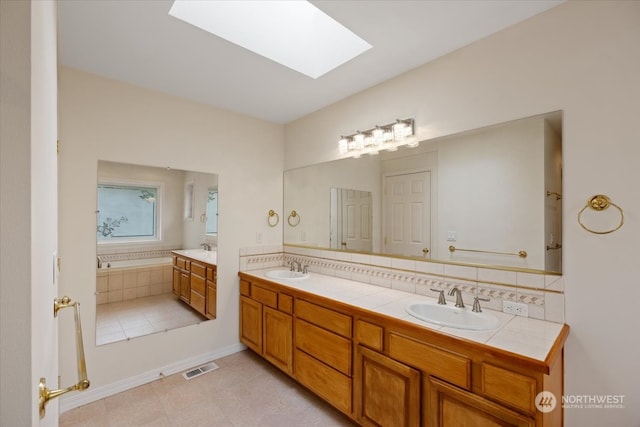 bathroom featuring a tub to relax in, a skylight, and vanity