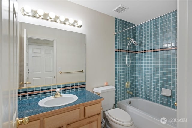 full bathroom with decorative backsplash, toilet, vanity, and tiled shower / bath