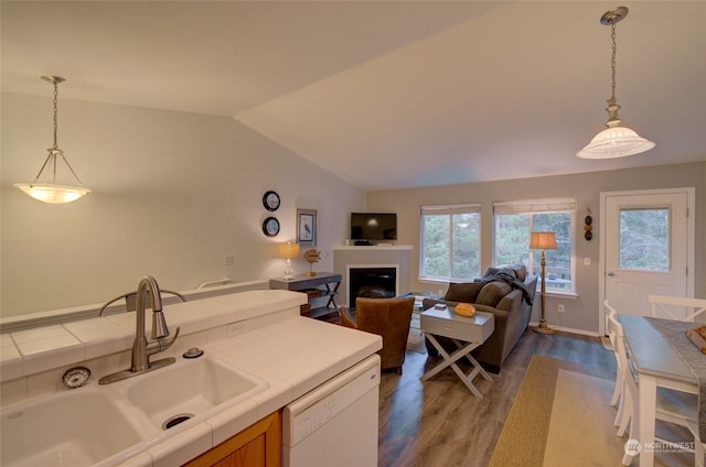 kitchen featuring dishwasher, sink, tile countertops, vaulted ceiling, and hardwood / wood-style flooring