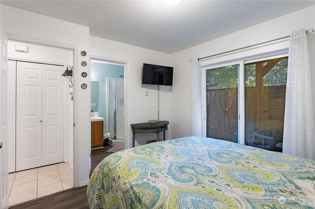 bedroom featuring dark wood-type flooring, access to outside, ensuite bathroom, a textured ceiling, and a closet