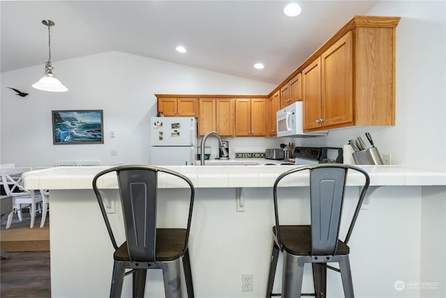 kitchen featuring a kitchen breakfast bar, lofted ceiling, dark hardwood / wood-style flooring, and white appliances