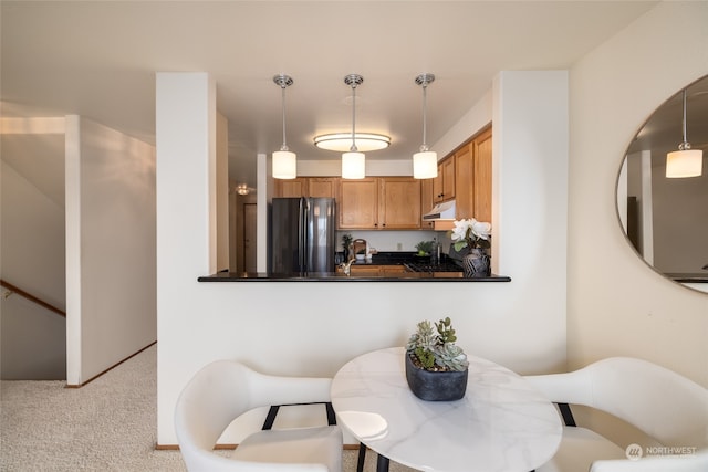 kitchen featuring kitchen peninsula, light carpet, decorative light fixtures, and stainless steel fridge