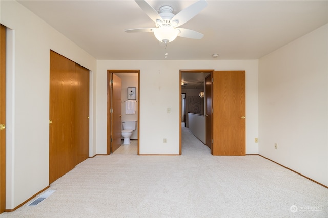 bedroom with a closet, light carpet, ceiling fan, and ensuite bath