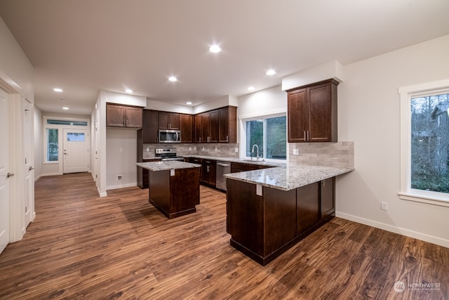 kitchen featuring dark hardwood / wood-style floors, kitchen peninsula, sink, and appliances with stainless steel finishes