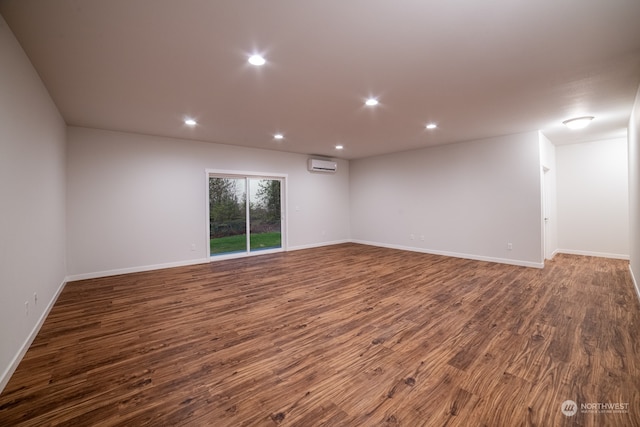 spare room with a wall unit AC and dark wood-type flooring