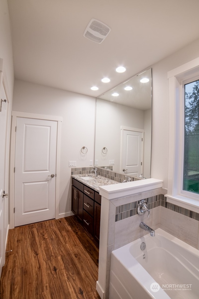 bathroom featuring hardwood / wood-style flooring, vanity, and a bathing tub