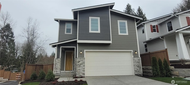 contemporary house with an attached garage, fence, stone siding, and driveway