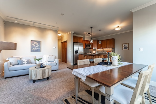 dining space featuring crown molding, sink, rail lighting, and light colored carpet