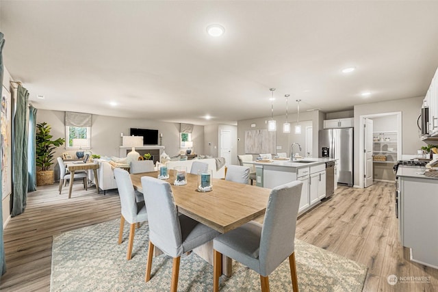 dining area with a fireplace, recessed lighting, and light wood-style floors