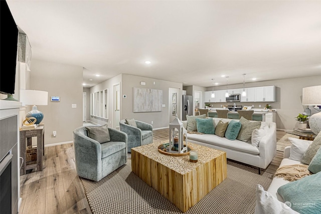 living room with light wood finished floors, recessed lighting, a fireplace, and baseboards