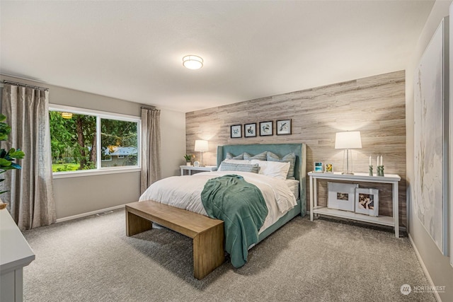 carpeted bedroom featuring wood walls, an accent wall, and baseboards