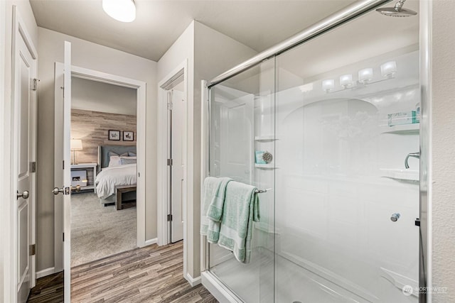 ensuite bathroom with connected bathroom, a stall shower, and wood finished floors