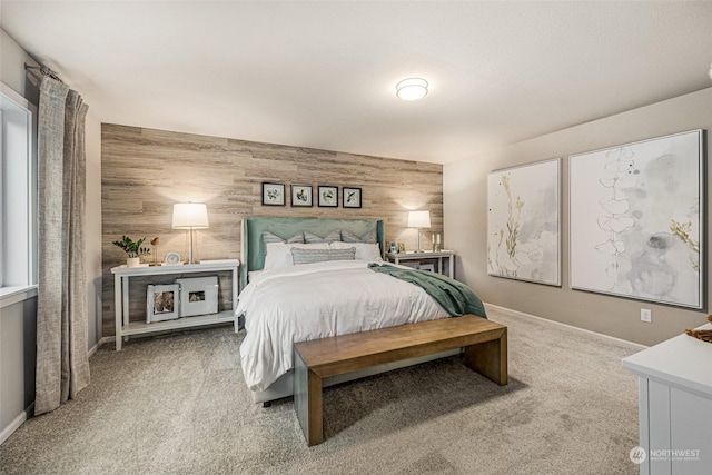 carpeted bedroom featuring an accent wall, wooden walls, and baseboards