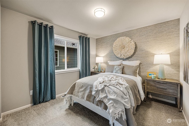 carpeted bedroom featuring an accent wall and baseboards