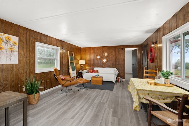 bedroom with light wood-type flooring, multiple windows, and wooden walls