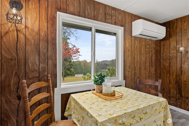 dining room with a wall unit AC, wood walls, a healthy amount of sunlight, and wood-type flooring