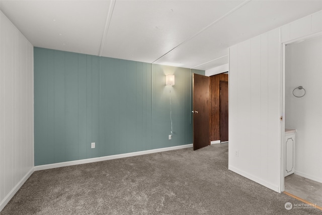 carpeted empty room featuring wooden walls