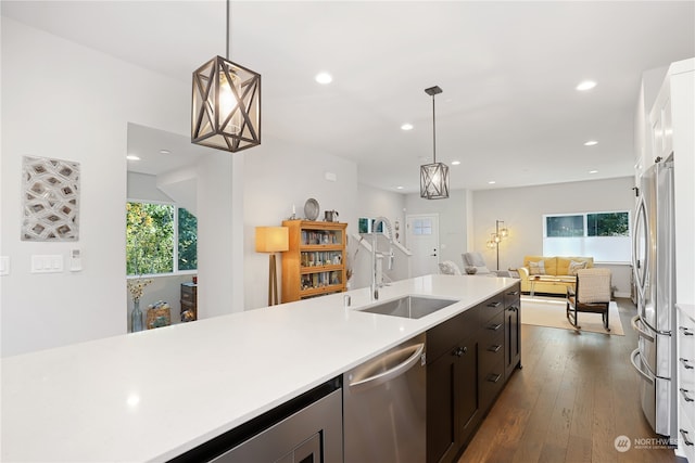 kitchen with appliances with stainless steel finishes, dark brown cabinetry, dark hardwood / wood-style flooring, hanging light fixtures, and sink