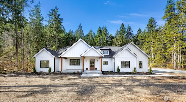 modern inspired farmhouse featuring board and batten siding and a view of trees