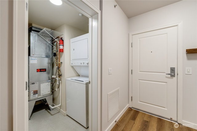 clothes washing area featuring light hardwood / wood-style floors and stacked washer and dryer