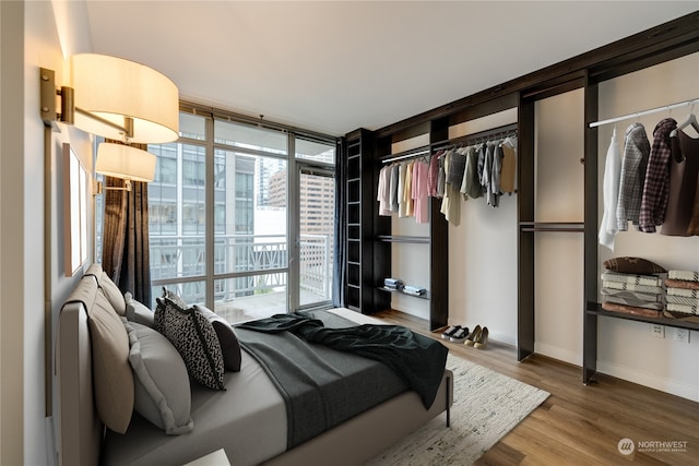 bedroom with a wall of windows, wood-type flooring, access to outside, and a closet